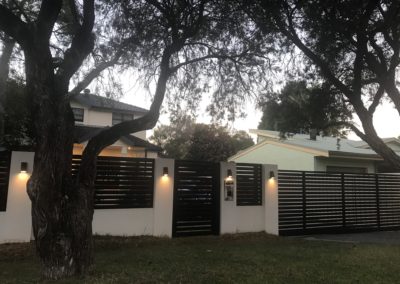 Modular wall with slatted aluminium sliding driveway gate, pedestrian gate and panels